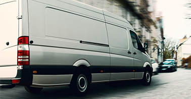 a plain white sprinter van drives down a cobblestone road